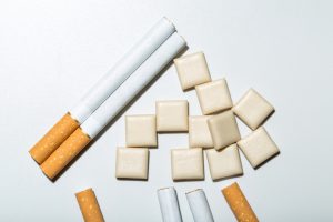 A close up of some cigarettes and nicotine chewing gum on a white background